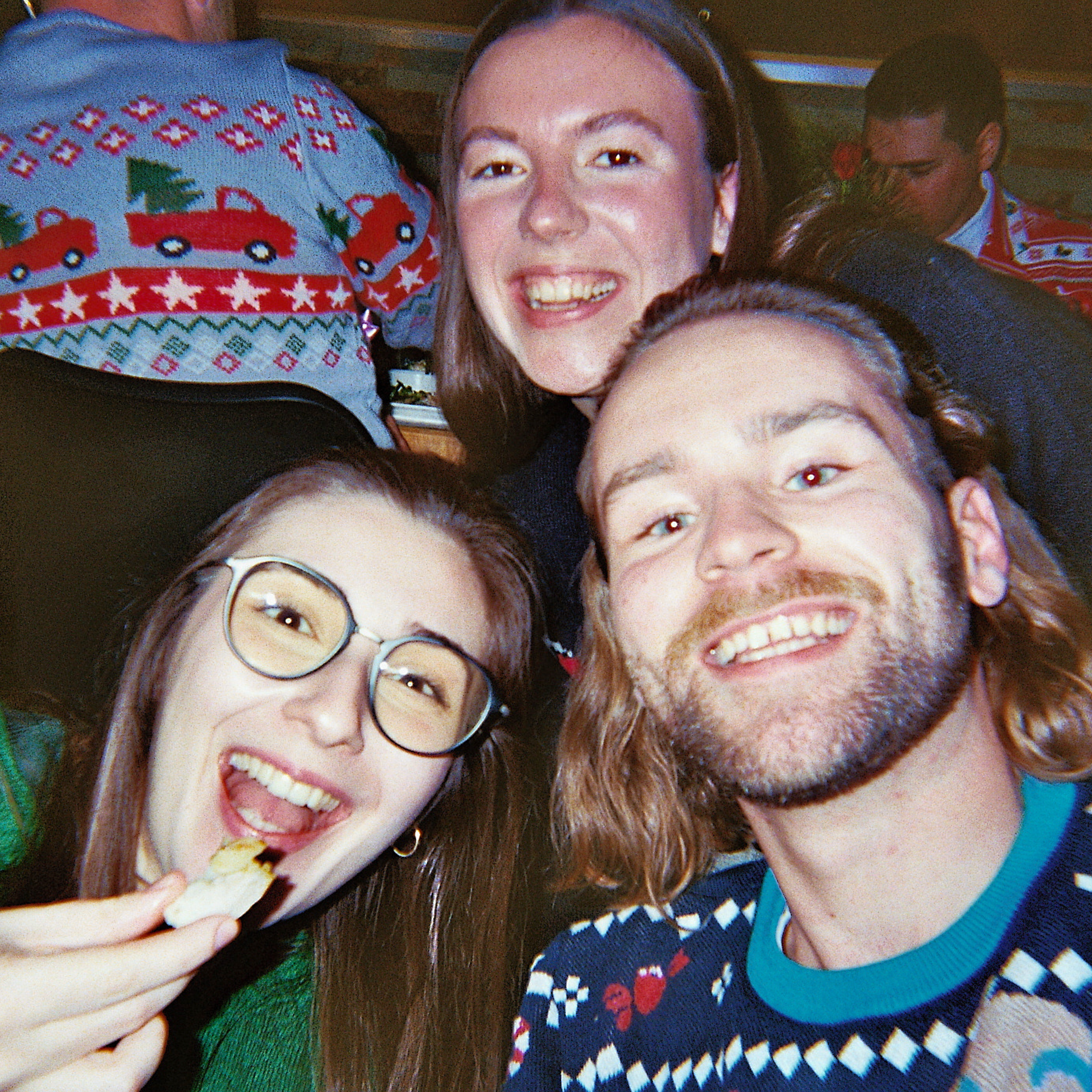 Drei Kollegen, die auf der Weihnachtsfeier in Weihnachtspullovern lachen